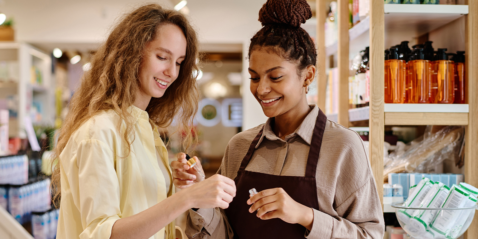 Numen propose des solutions de confection de cartes fidélité. Image de deux femmes dans une boutique. La première conseille la seconde dans l'achat d'un produit. Cette image traduit la notion d'accompagnement et de fidélité.