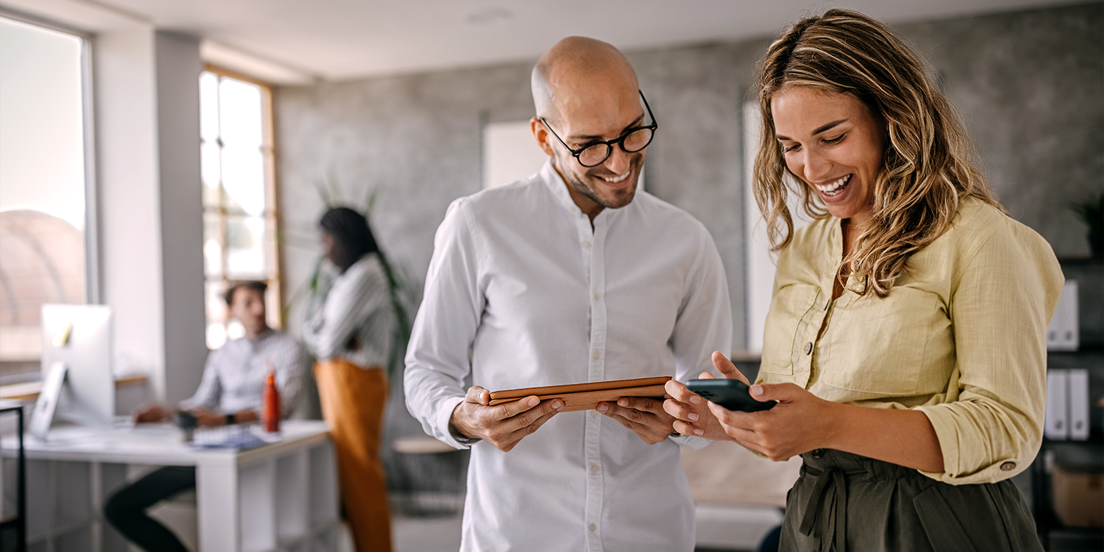 L'éditique industrielle renforce votre image de marque. Homme et femme souriants devant une tablette