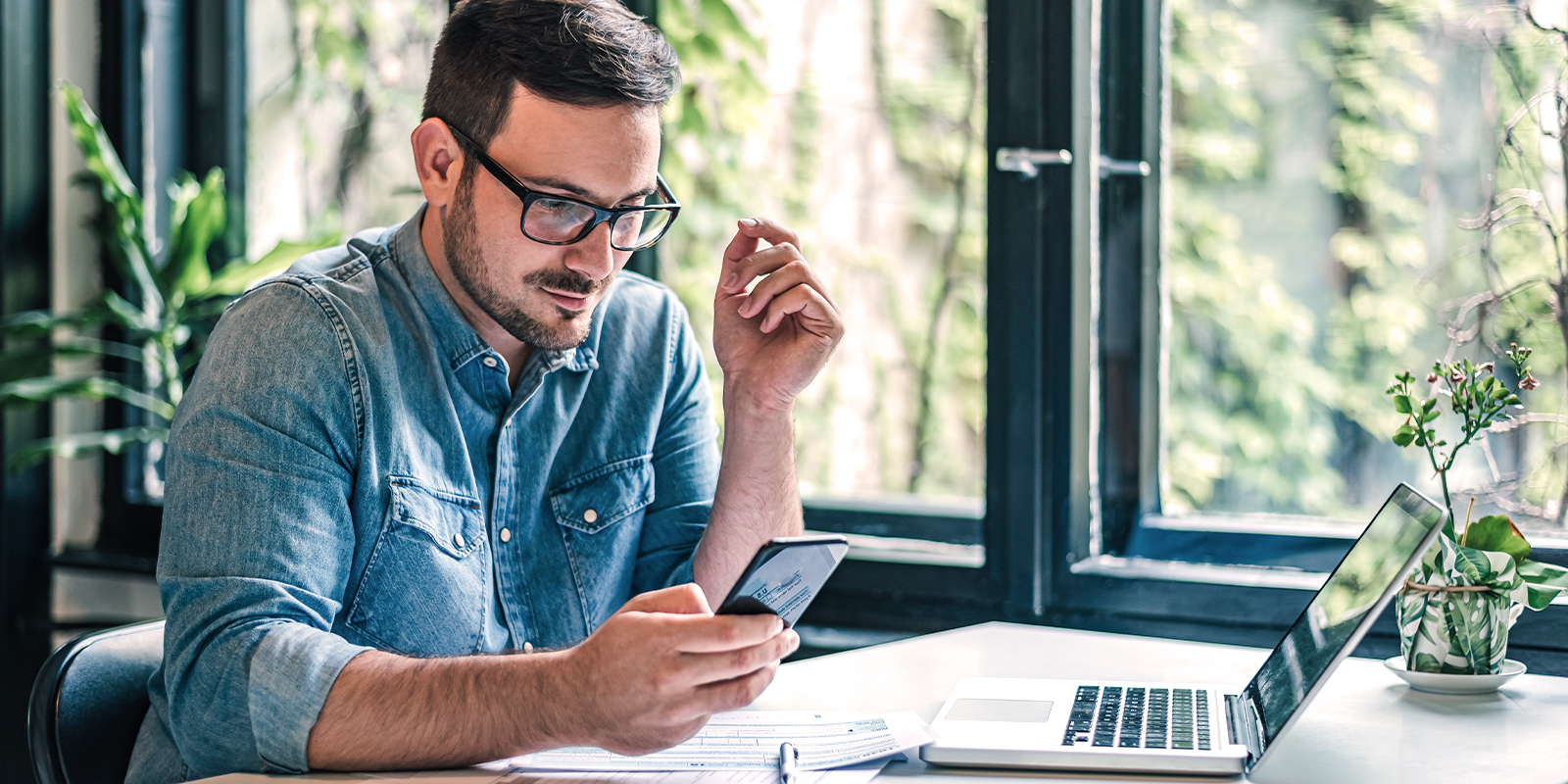 Numen propose des services additionnels à son offre d'externalisation de la fabrication des carnets de chèques : notifications SMS ou email, webchèque et webreporting. Image d'un homme content de recevoir une alerte via sms pour avoir le suivi de sa commande de carnets de chèques.