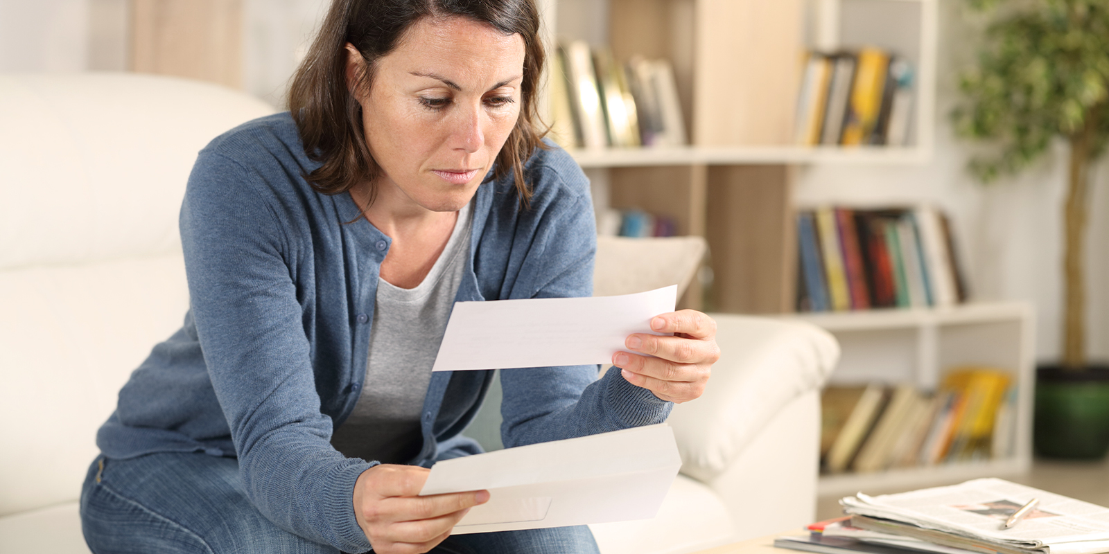 La production et l'envoi de lettres chèques est flexible et traçable grâce à Numen. Image d'une femme ouvrant une lettre chèque à son domicile.